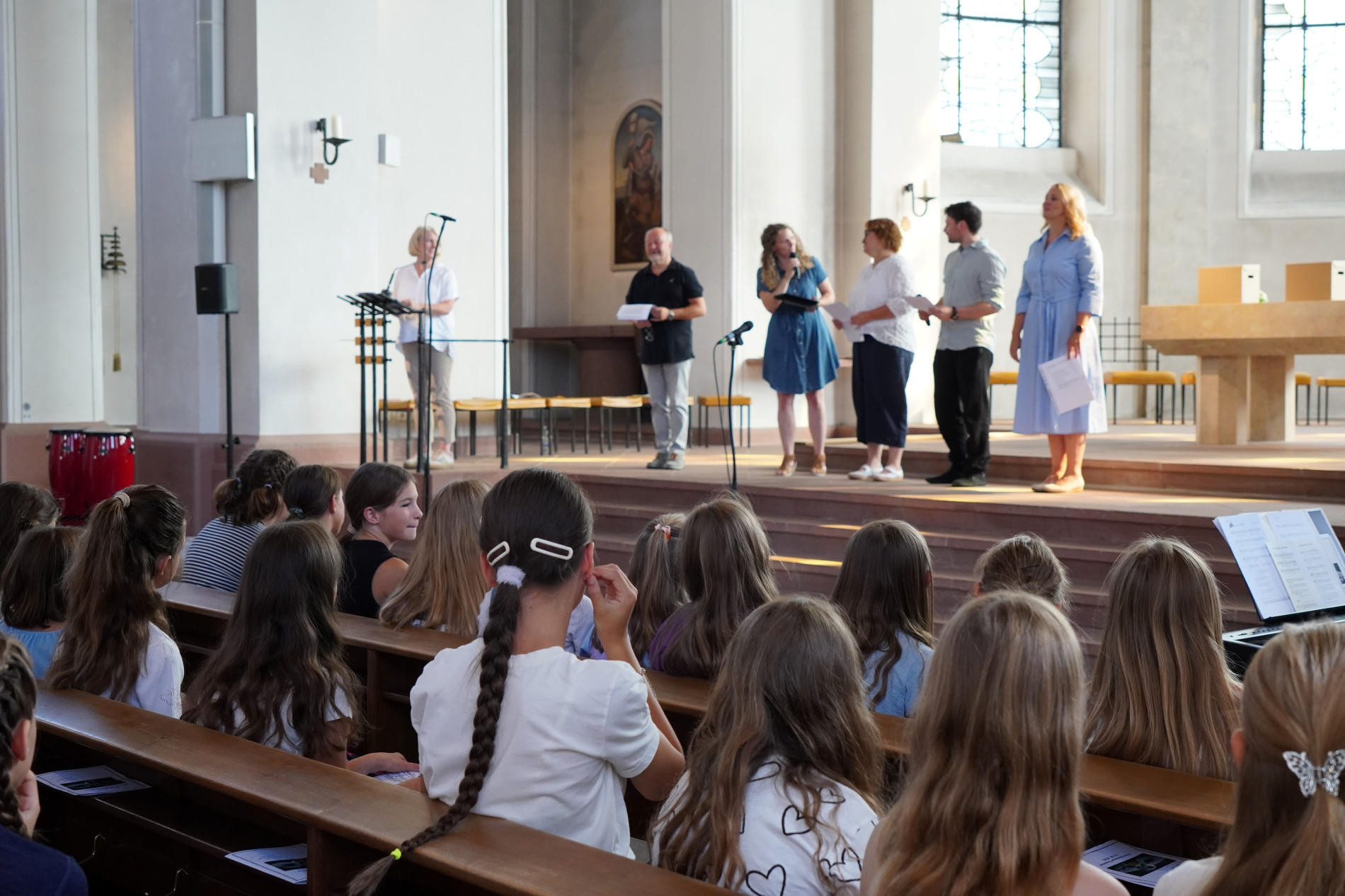Blick auf die neuen Fünftklässlerinnen während des Einschulungsgottesdienstes. Vorne gestalten mehrere Erwachsene das Programm.
