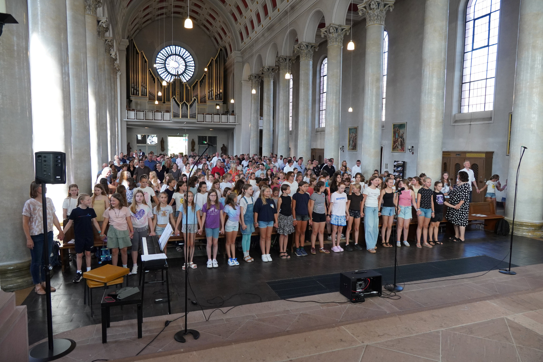 Die neuen Fünftklässlerinnen stehen gemeinsam in der Kirche. Hinter ihnen sind Familien und weitere Gäste zu sehen.