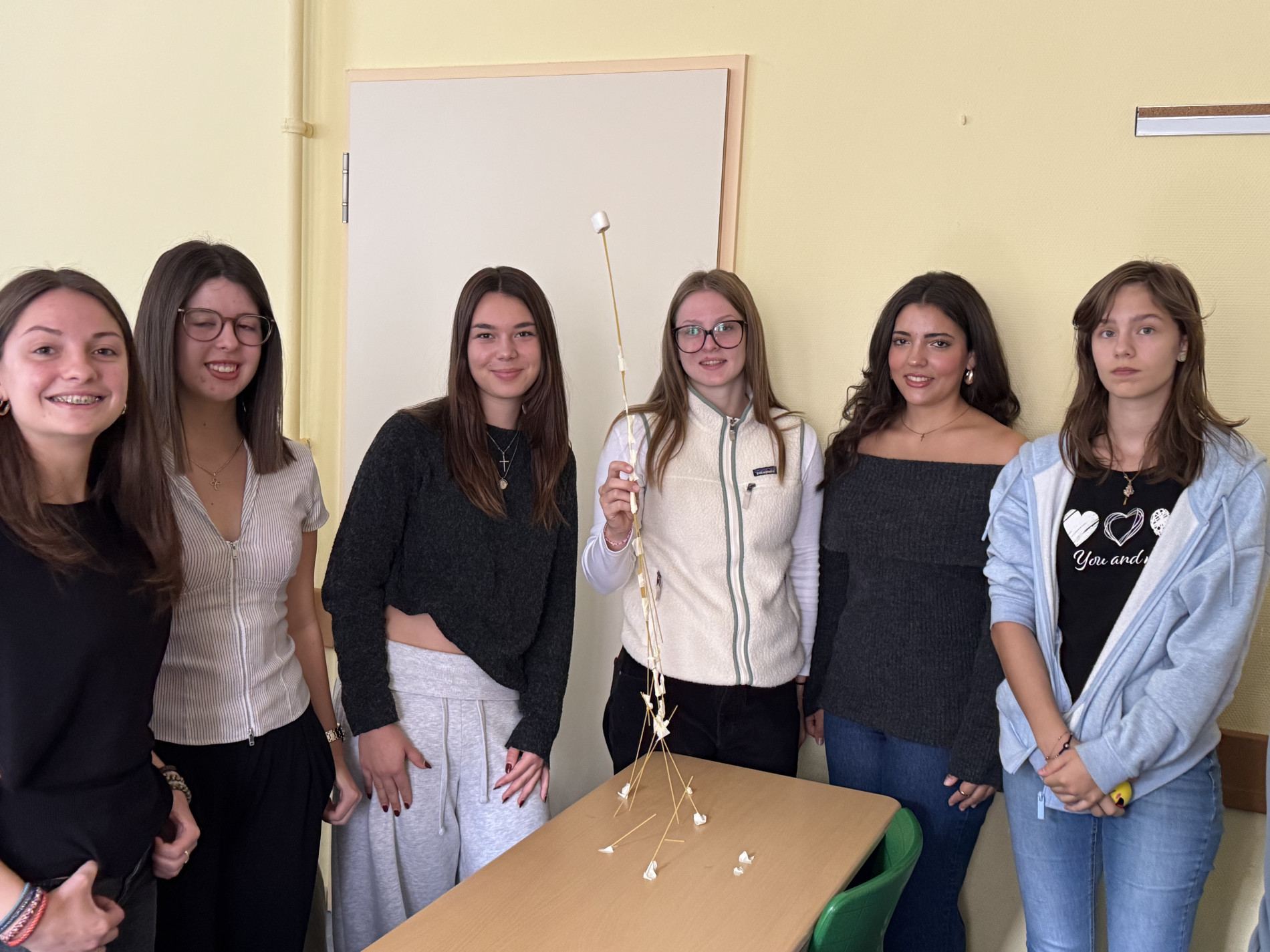 Sechs Schülerinnen präsentieren ihren hohen Spaghetti-Turm mit einem Marshmallow an der Spitze. Sechs Schülerinnen präsentieren ihren hohen Spaghetti-Turm mit einem Marshmallow an der Spitze.