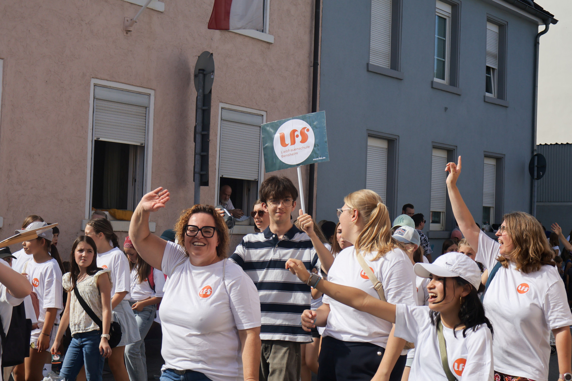 Schülerinnen und erwachsene Begleitpersonen der Liebfrauenschule laufen gemeinsam beim Winzerfestumzug mit, winken und tanzen. Schülerinnen und erwachsene Begleitpersonen der Liebfrauenschule laufen gemeinsam beim Winzerfestumzug mit, winken und tanzen.