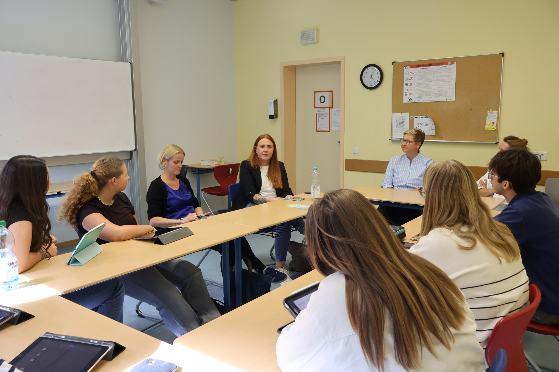 Schülerinnen und Schüler sitzen an zusammengestellten Tischen und hören im Unterrichtsgespräch zu. Schülerinnen und Schüler sitzen an zusammengestellten Tischen und hören im Unterrichtsgespräch zu.